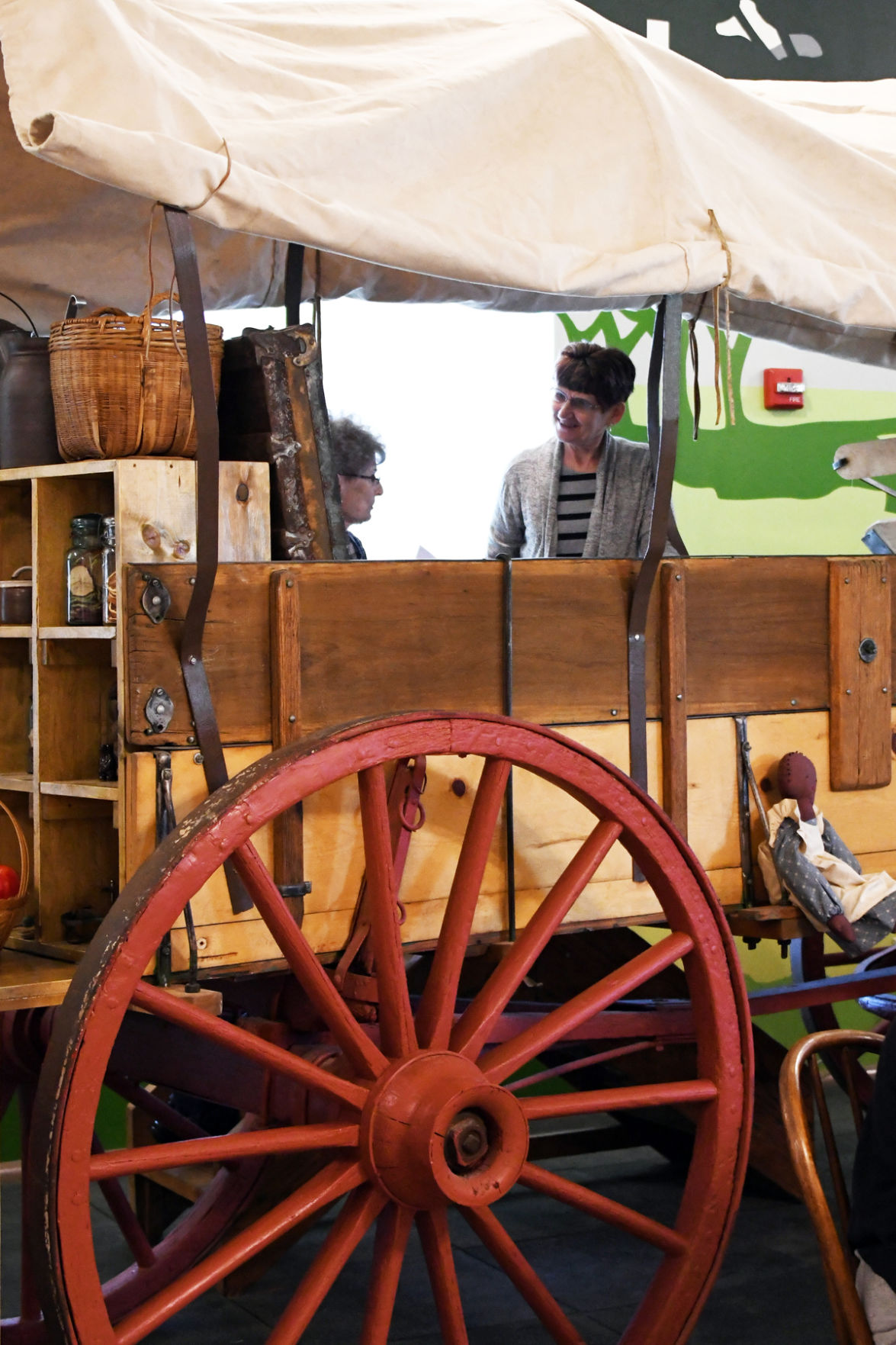 083 Marlene Larson and Doris Rogers climb aboard the covered wagon at the Mead Center.JPG